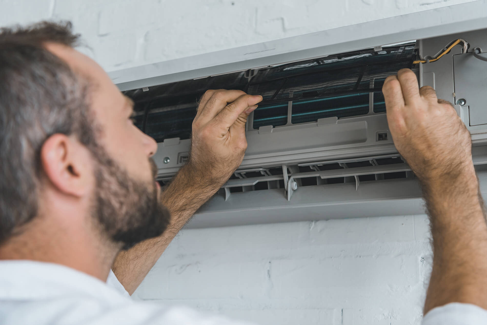 Photo of an HVAC repairperson fixing an AC unit